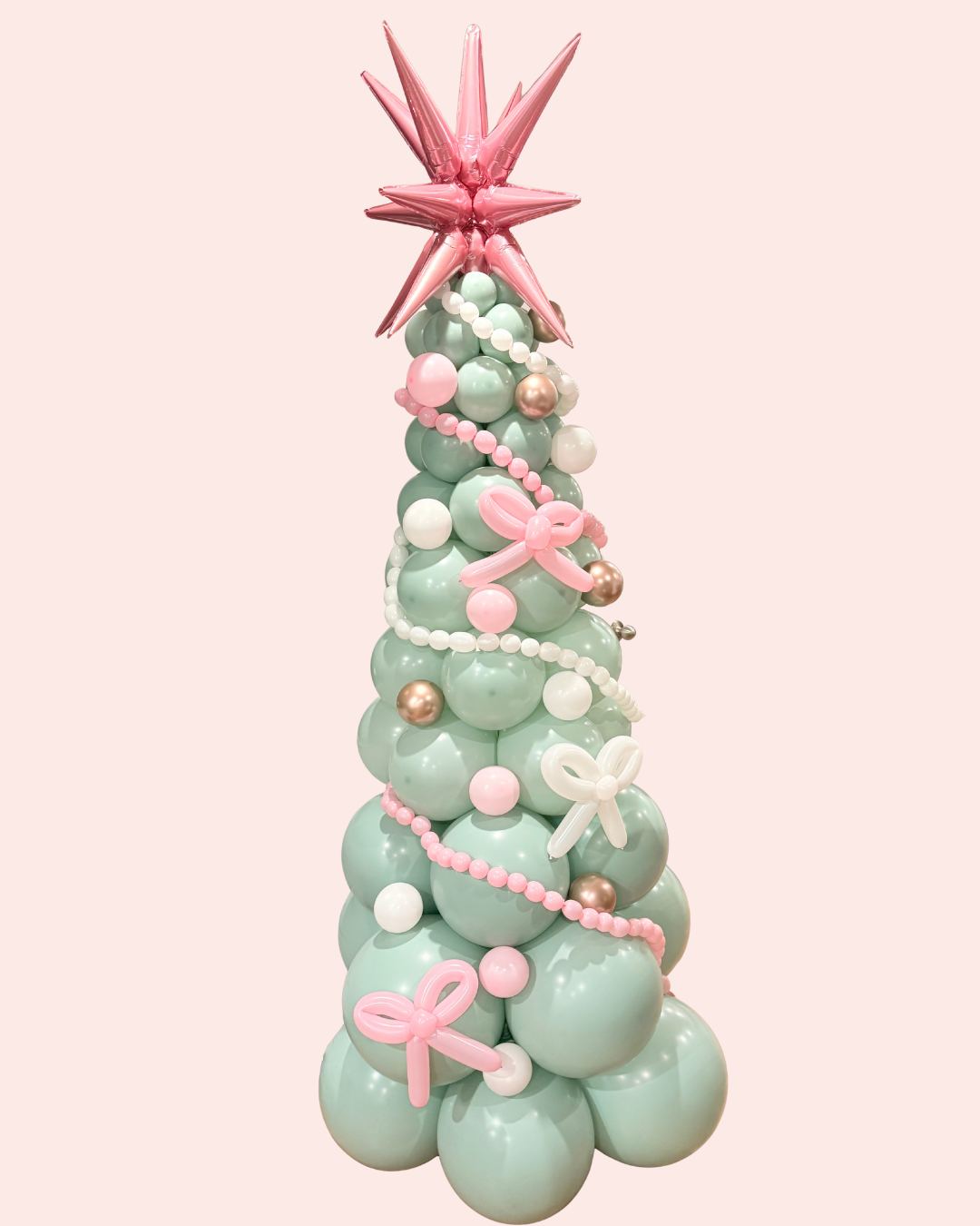 Sage green balloon tree trimmed with pink bows under a pink star topper