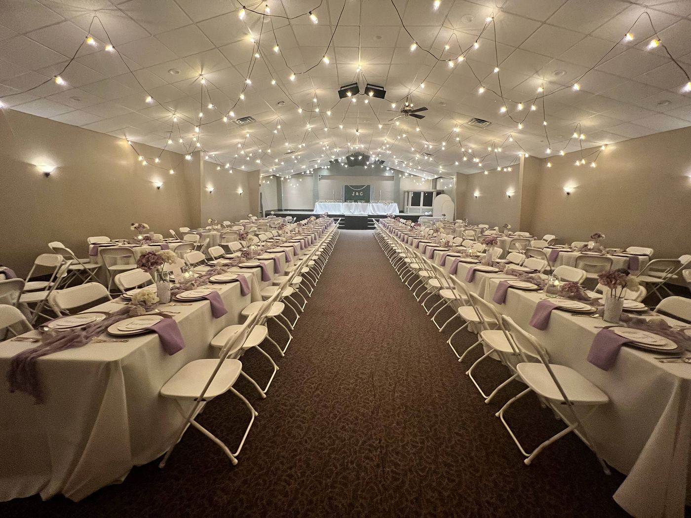 Event hall set with long rows of dressed tables under string lights