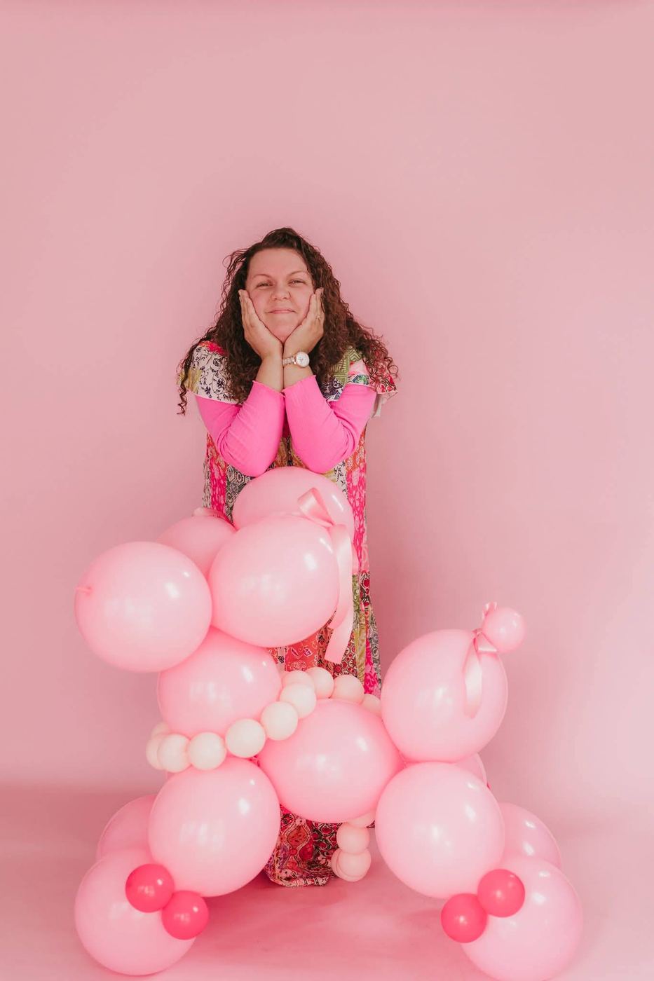 Jo, owner of Enchanted Events by Jo, smiling among pink balloons