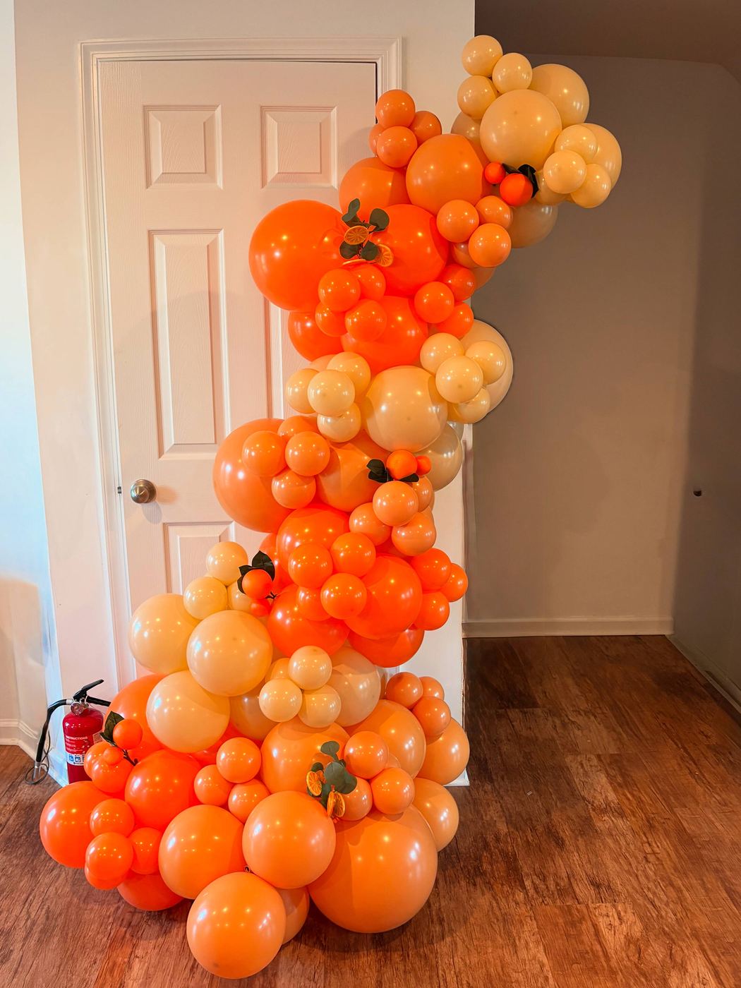 Tall cascading orange balloon column in a doorway