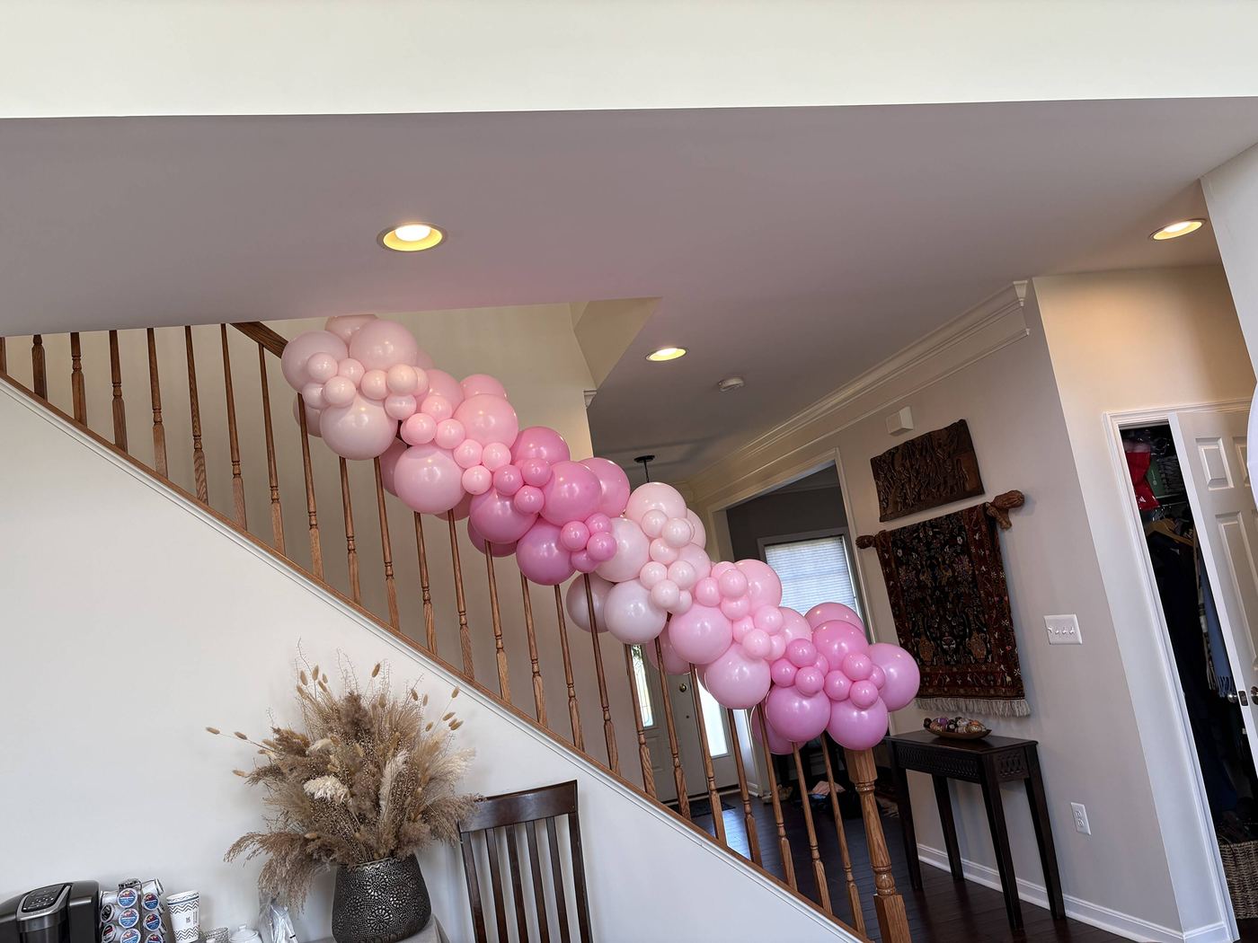Pink, mauve and white balloon garland running along a staircase railing