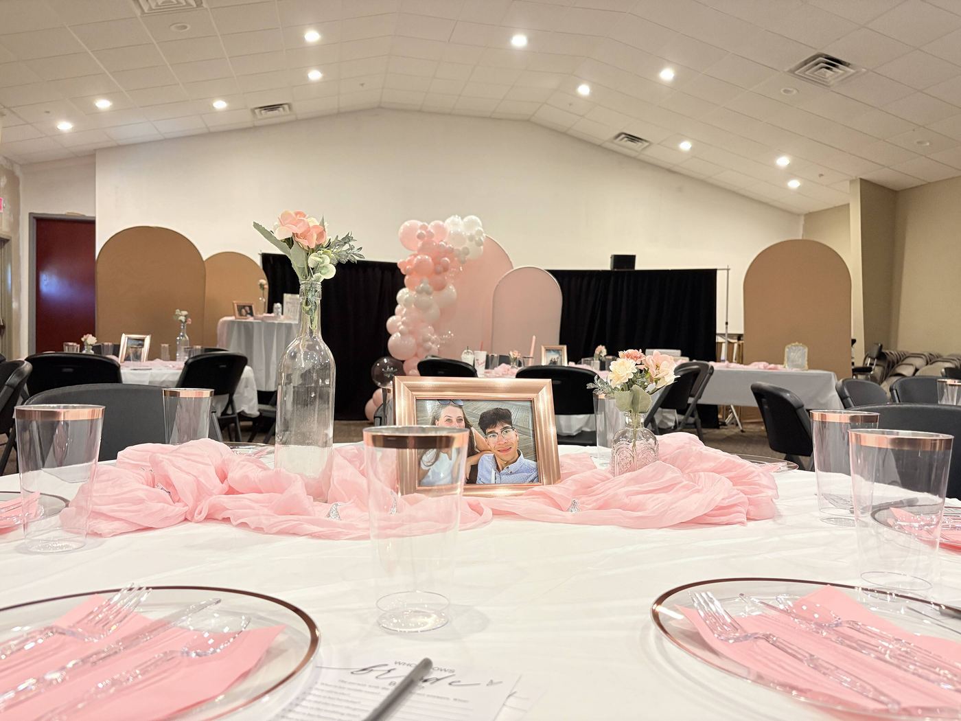 Pink and white place settings with balloon centerpieces on a dressed banquet table